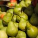 Vibrant green pears and apples displayed at a farmers' market.