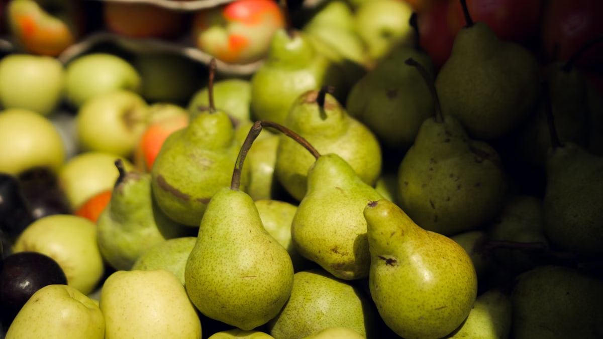 Vibrant green pears and apples displayed at a farmers' market.